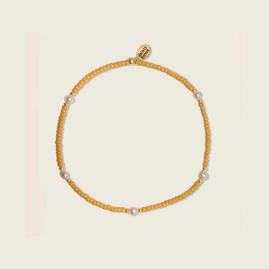 Golden Hour bracelet crafted with light orange beads, 14k gold filled beads, and freshwater pearls