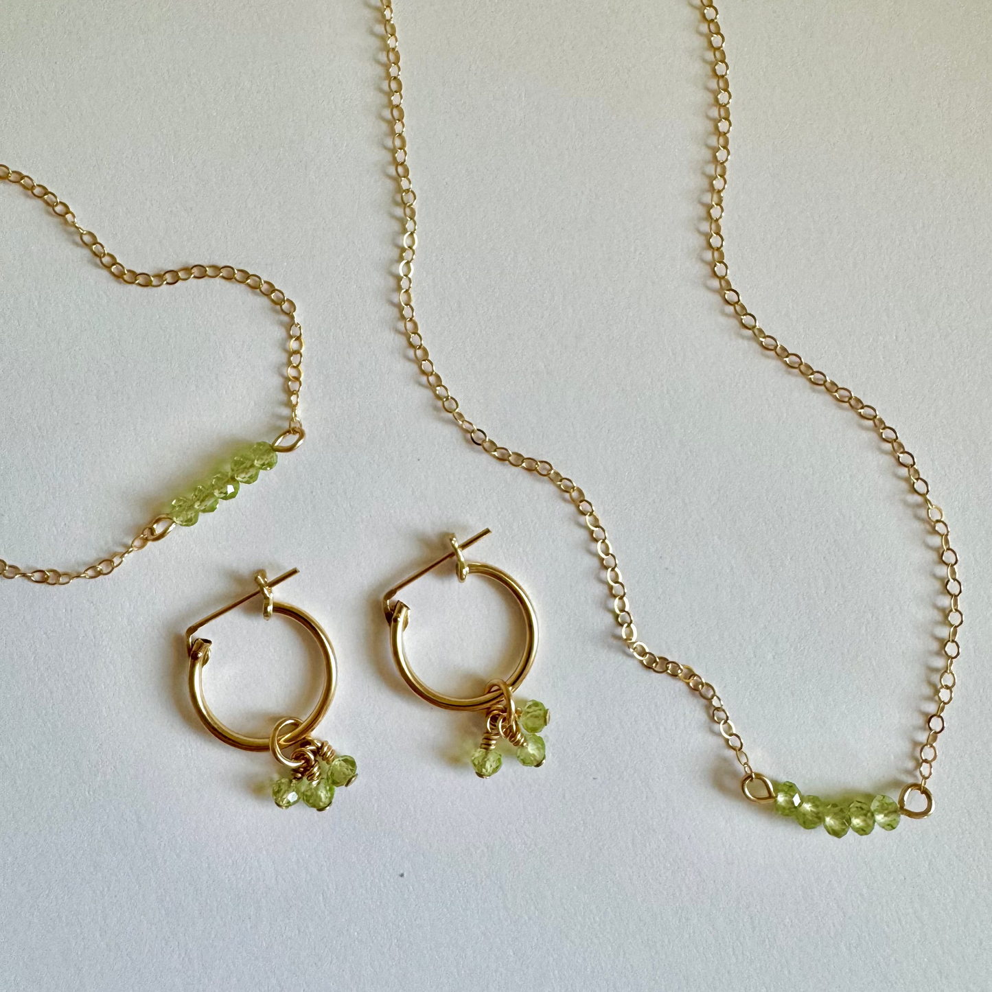 Gold necklace and earrings with green beads on a white background