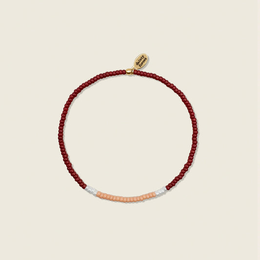 A beaded bracelet with red, light peach, and white pearls miyuki beads, displayed against a neutral background.