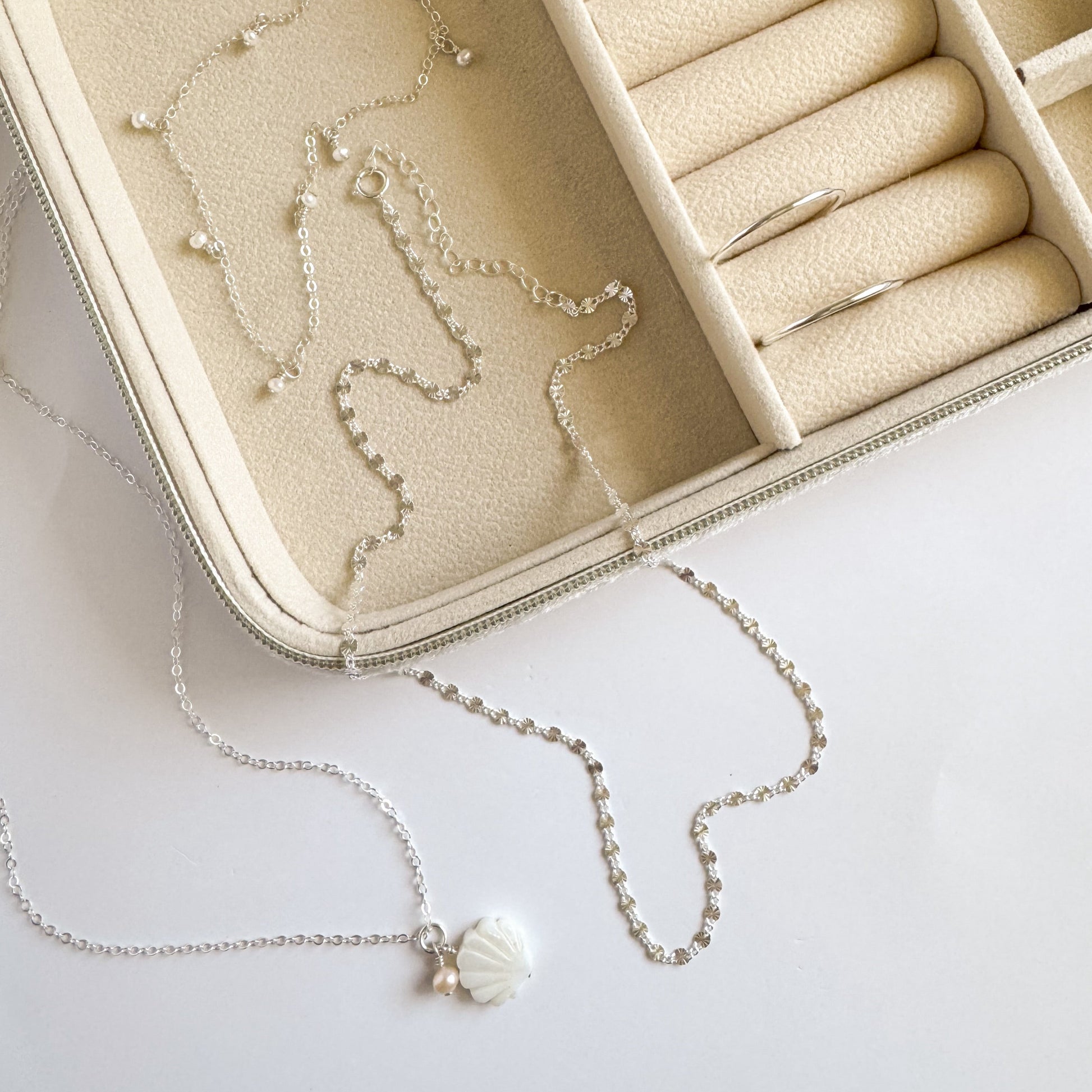 Necklace with a pendant on a white surface next to an open jewelry box.