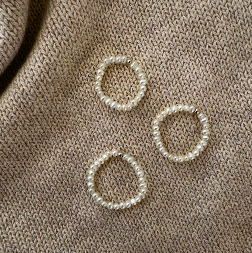 Three pearl-like circular objects on a beige knitted fabric background