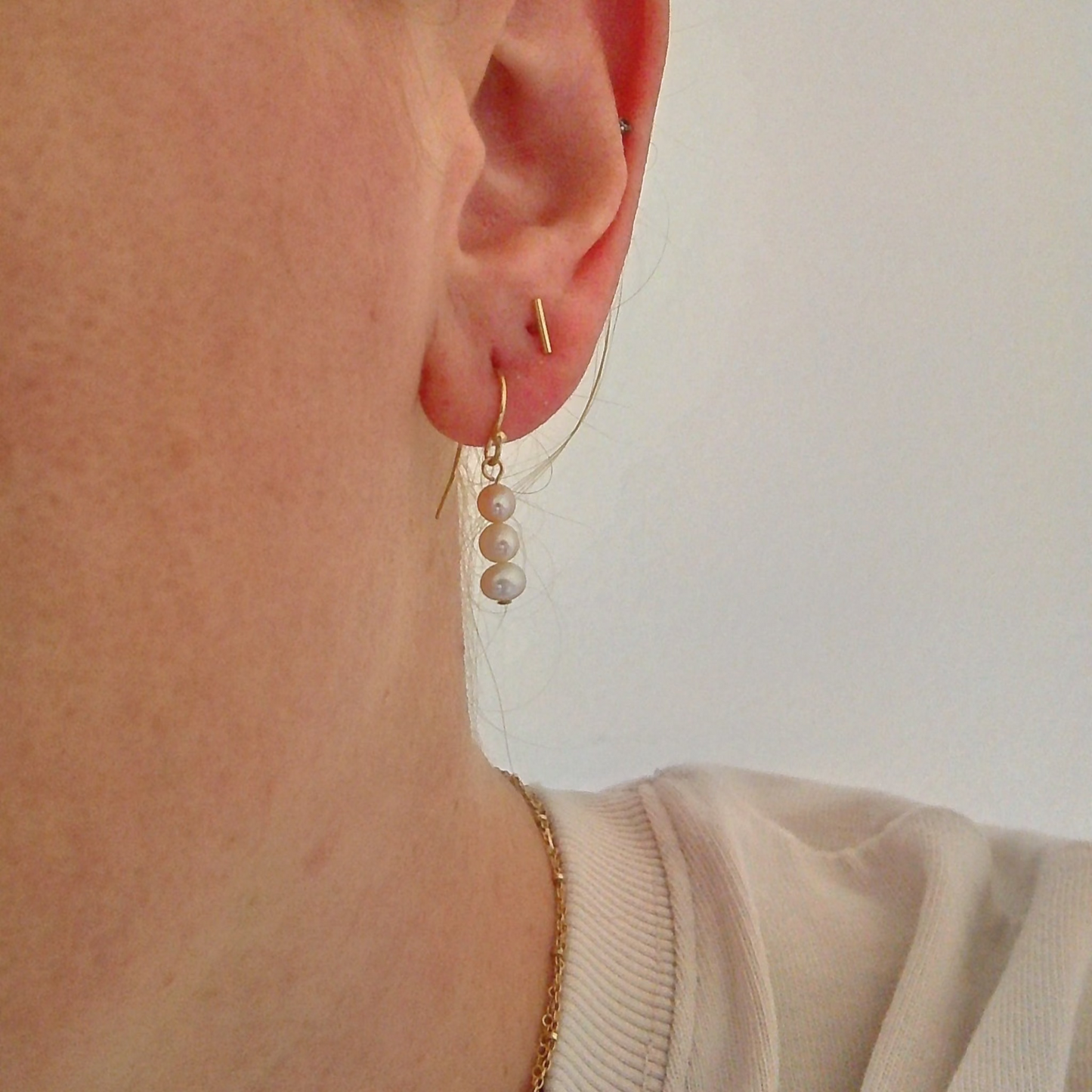 Close-up of an ear wearing a pearl earring with a plain background