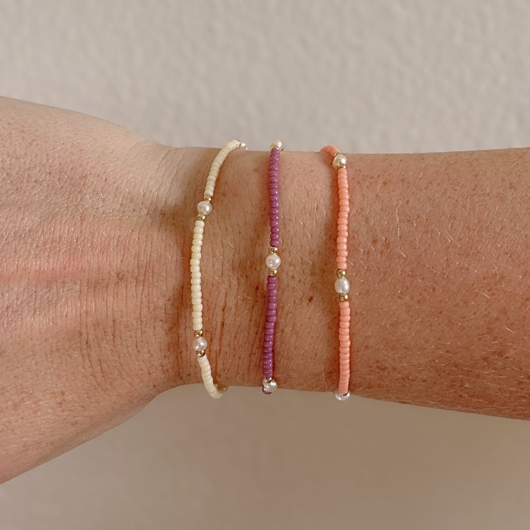 Three beaded bracelets on a wrist against a neutral background