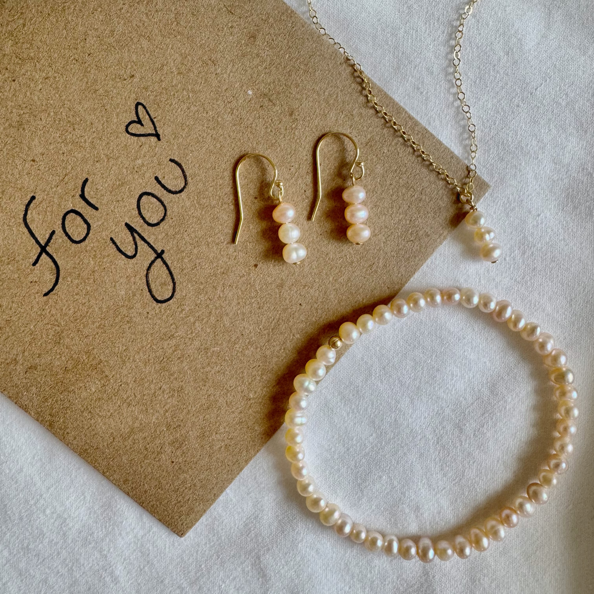 Pearl jewelry set including necklace, earrings, and bracelet on a 'for you' card.