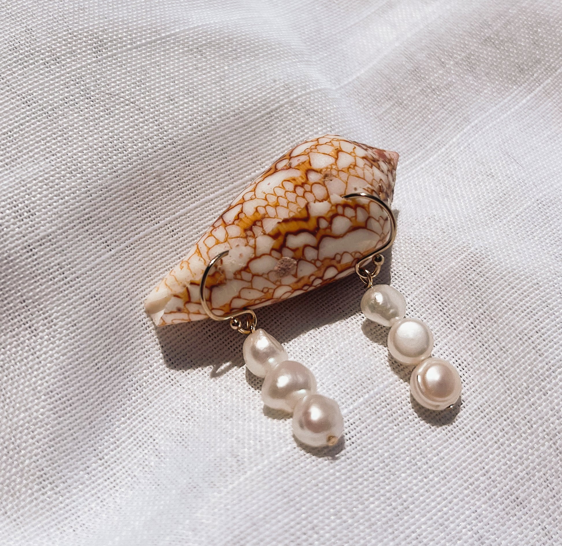 3-drop pearl earrings elegantly displayed on a seashell, showcasing timeless sophistication and natural beauty.