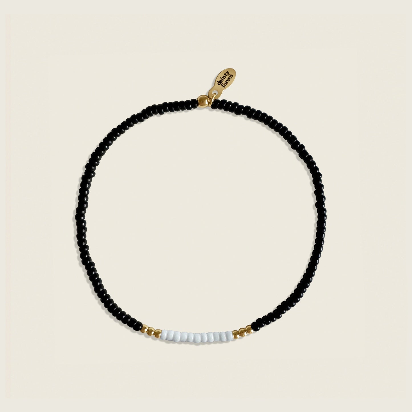 Black beaded necklace with gold and white accents on a beige background