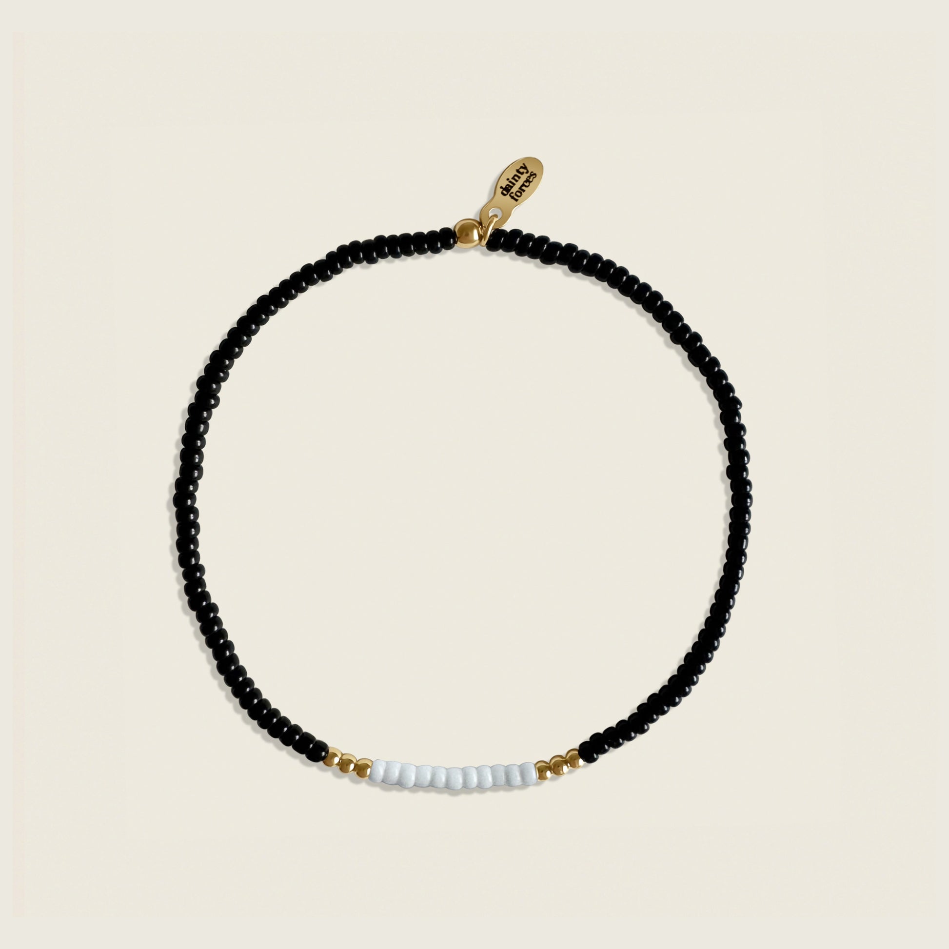 Black beaded necklace with gold and white accents on a beige background