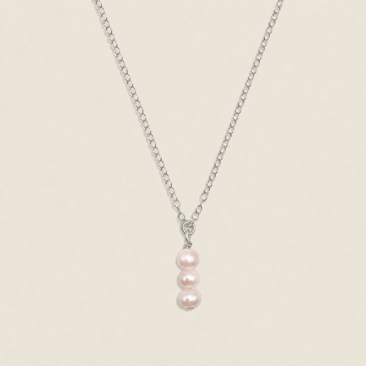 Pearl necklace with a silver chain on a beige background