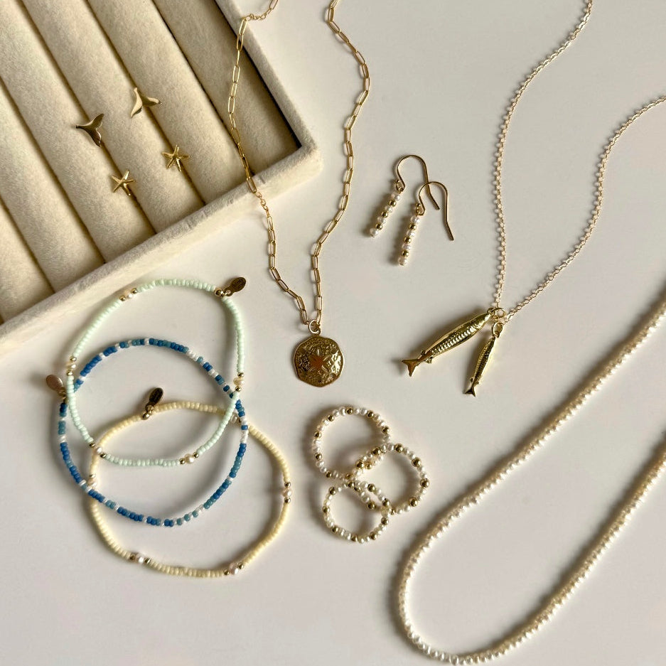 Collection of gold and silver jewelry including necklaces, bracelets, and earrings on a light background.