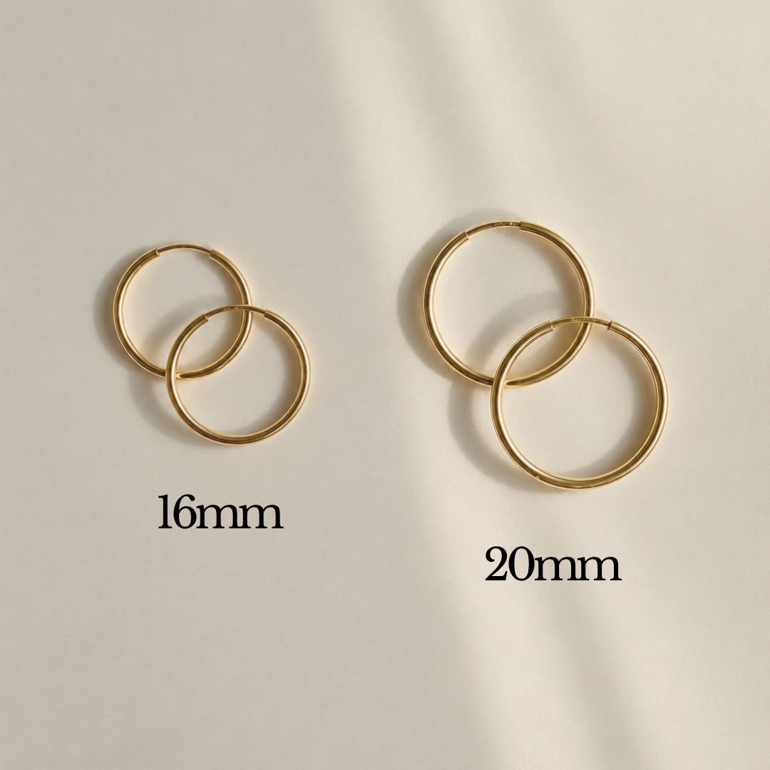 Two pairs of gold hoop earrings shown on a light beige background, one labeled 16mm and the other labeled 20mm, with soft diagonal shadows across the scene.