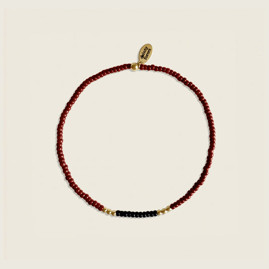 Necklace with red, black, and gold beads on a beige background