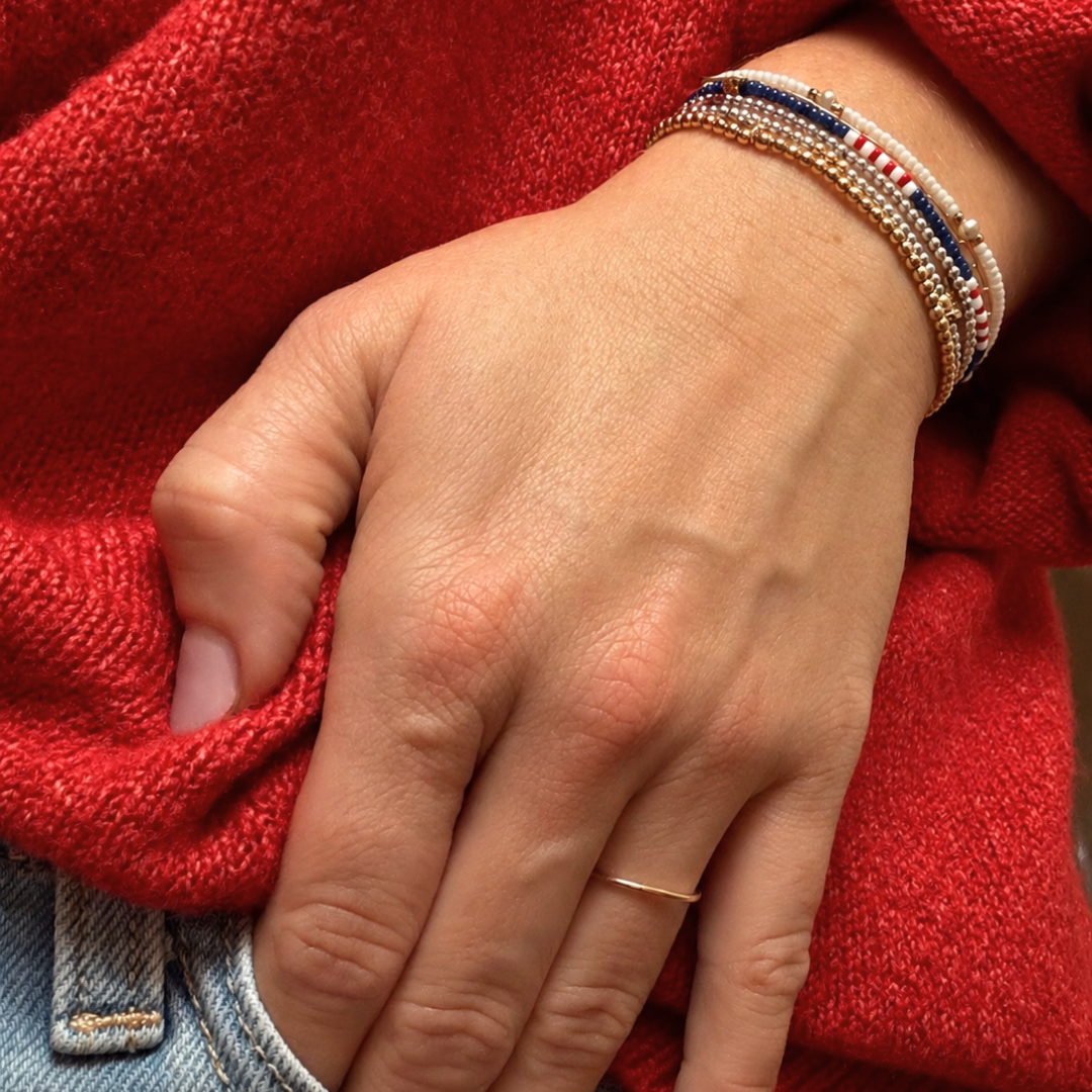gold and silver stacking bracelets on wrist with americana blue white and red layering bracelet with the oyster shell braclet 